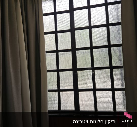 חלון עם תריסים שחורים ומסגרת מתכת